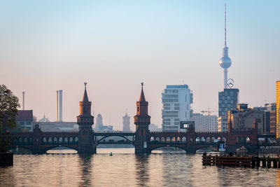 Bridge over river by buildings against sky in city