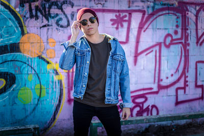 Full length of young man standing against graffiti wall