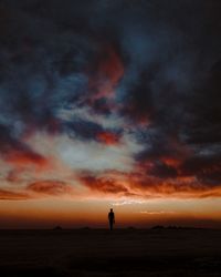 Silhouette people standing on beach against sky during sunset