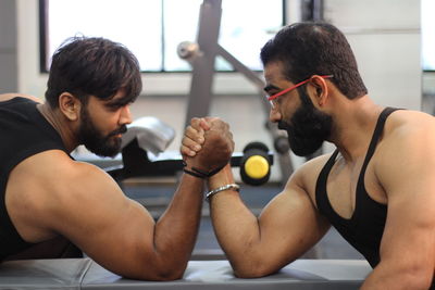 Male friends arm wrestling at gym