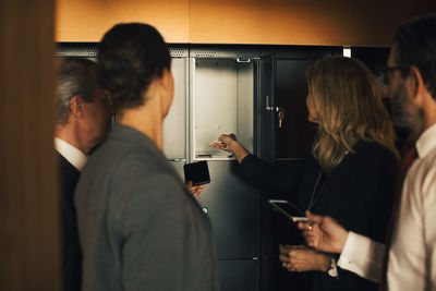 Male and female professionals keeping smart phones in locker at legal office