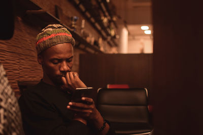 Young man using smart phone in restaurant