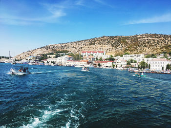 Scenic view of sea by buildings against blue sky