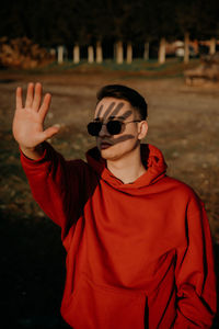 Man wearing sunglasses shielding eyes while standing outdoors