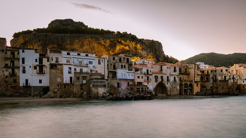 Buildings by river in town against clear sky