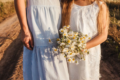 Midsection of woman holding white flower