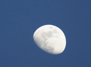 Low angle view of half moon against clear blue sky