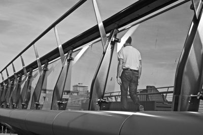 Rear view of man standing on boat sailing against sky