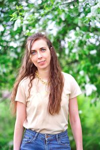 Portrait of a beautiful young woman standing against plants