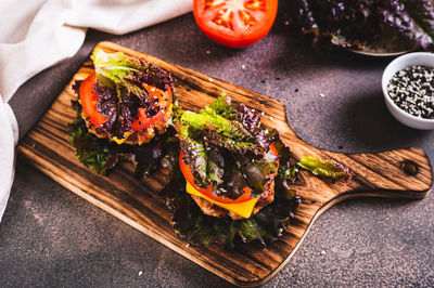 Juicy keto burgers on fresh lettuce leaves of cutlet, tomato and cheese on a board on the table