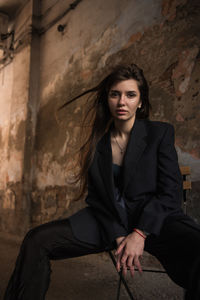 Portrait of woman sitting against wall