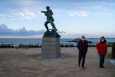 Statue of man standing by sea against sky