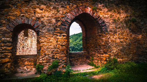 Old ruin building against sky seen through arch