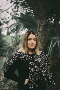 Young woman standing against tree