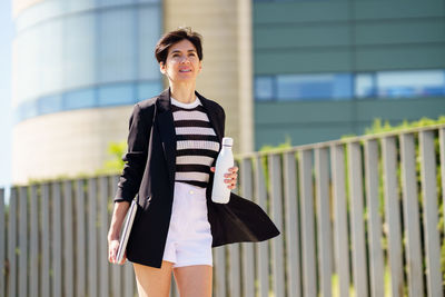 Young woman standing against building