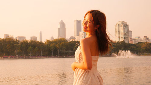Portrait of young woman standing against river