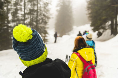 Rear view of people on snow covered field during winter