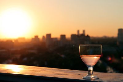Close-up of wineglass against sky during sunset