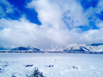 Scenic view of snow covered mountains against cloudy sky