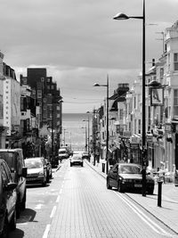 Cars on street in city against sky