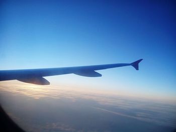 Cropped image of airplane flying over cloudscape against blue sky