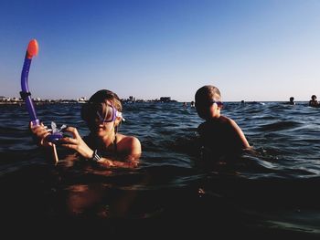 Portrait of friends enjoying in sea against clear sky