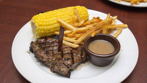 Close-up steak served with corn and fries