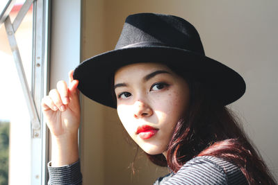 Portrait of young woman wearing hat and lipstick at home