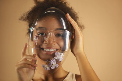 Portrait of young woman wearing mask against yellow background