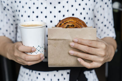 Midsection of woman holding coffee cup ad food