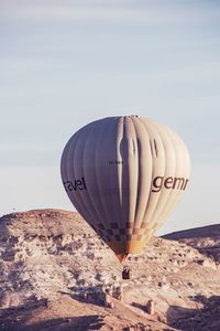 Hot air balloon flying over mountain against clear sky