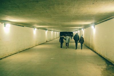 Rear view of men standing in illuminated corridor