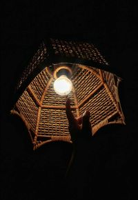 Low angle view of illuminated lighting equipment against black background