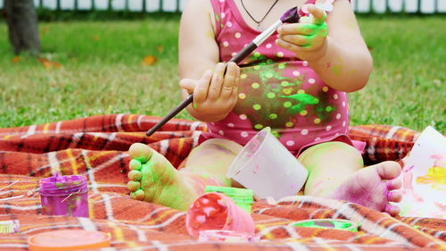 A little child, a one-year-old girl playing, painting with finger paints, decorating herself, in