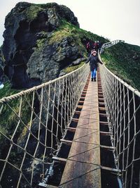 Rear view of man walking on footbridge