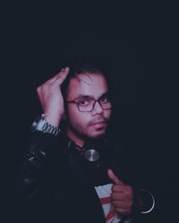 Portrait of young man wearing eyeglasses against black background