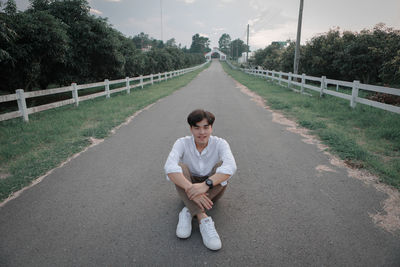 Portrait of smiling man sitting on road