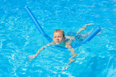 High angle portrait of smiling boy swimming in pool