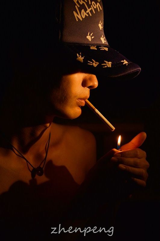 indoors, lifestyles, young adult, black background, leisure activity, front view, holding, close-up, person, studio shot, headshot, dark, night, young men, bad habit, addiction