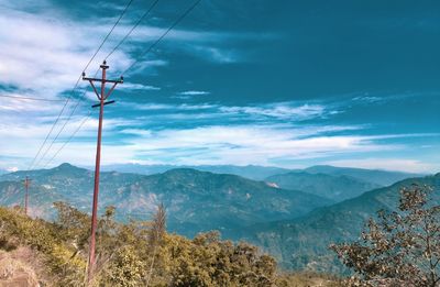 Electricity pylon by mountains against sky