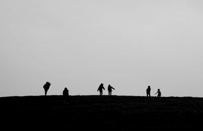 Silhouette people enjoying on field against clear sky