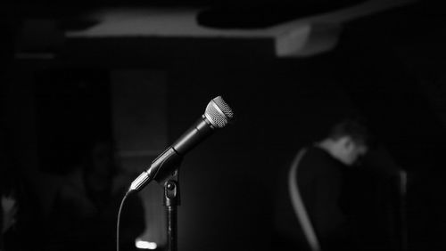Close-up of microphone against musician standing in recording studio