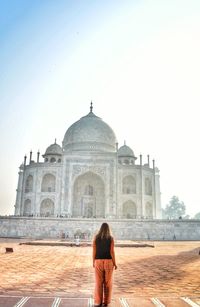 Rear view of woman standing in front of historical building