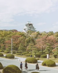 Rear view of people walking on footpath against sky