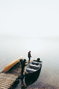 Man and child getting ready to go fishing in a boat on a foggy day.