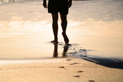Low section of man walking on beach