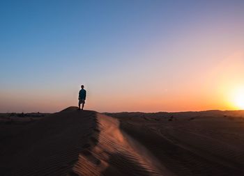 Man walking on desert at sunset