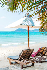 Deck chairs on beach against sky