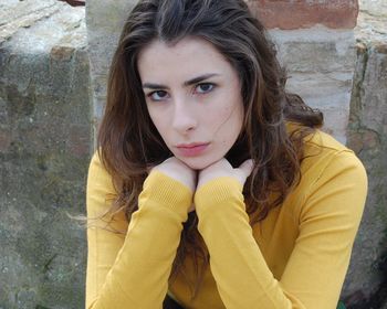 Portrait of woman sitting against wall
