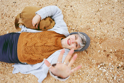 Directly above portrait of young woman lying at beach